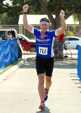 Athlete approaches finish line with arms raised overhead